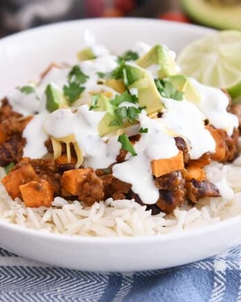 white rice topped with sweet potato black bean burrito ingredients, avocados, cilantro and limes