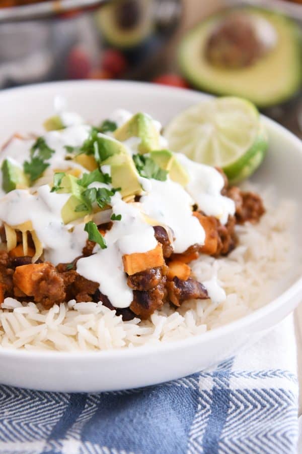 white rice topped with sweet potato black bean burrito ingredients, avocados, cilantro and limes