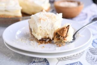 bite taken out of banana coconut cream pie on white plate with fork