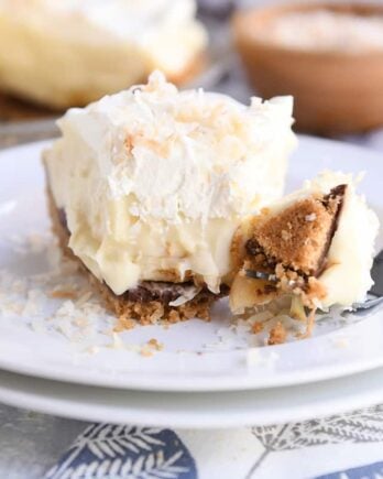 bite taken out of banana coconut cream pie on white plate with fork