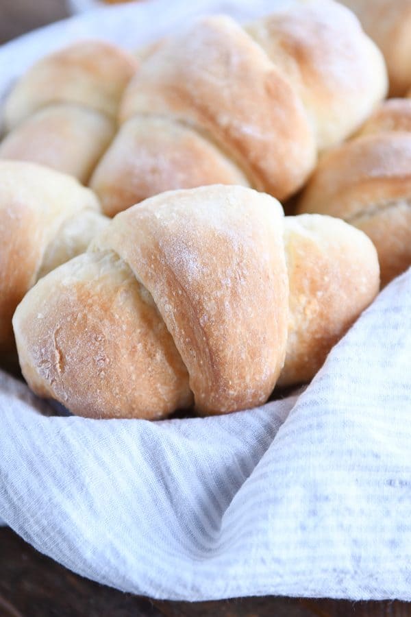 Crescent rolls in basket with brown and white striped napkin.