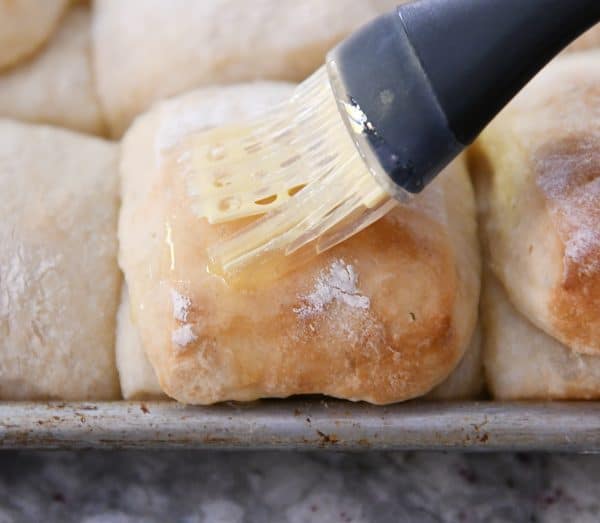 brushing melted butter on warm roll with pastry brush