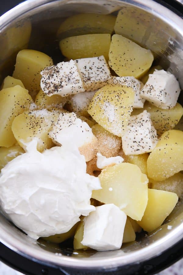 Instant pot of cooked potatoes, sour cream, butter, and cream cheese.