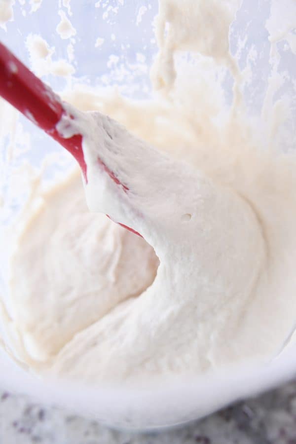 stirring sourdough starter in bucket with red rubber spatula