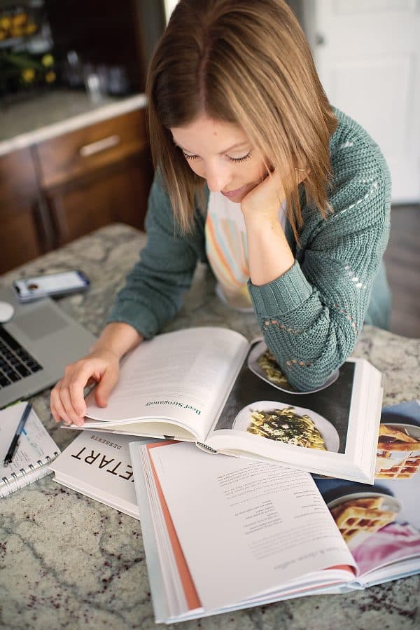 woman in green cardigan looking at cookbook