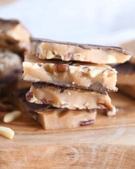 four pieces of homemade toffee stacked on wood cutting board