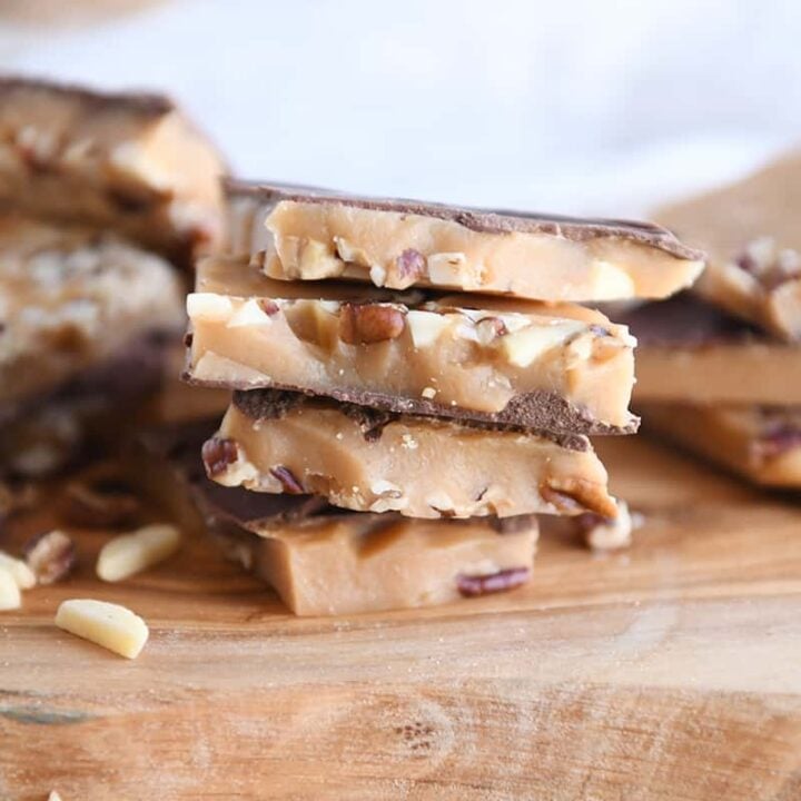 four pieces of homemade toffee stacked on wood cutting board