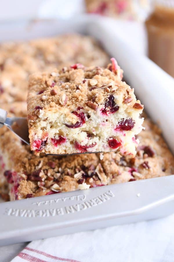 Square of cranberry coffee cake on spatula over 9x13-inch pan.