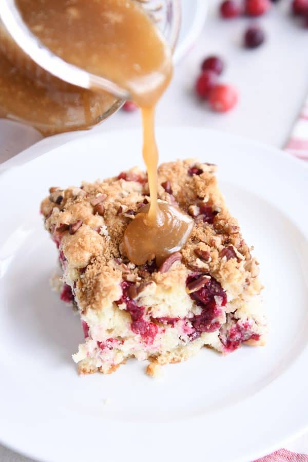 Pouring warm vanilla sauce over piece of cranberry coffee cake.