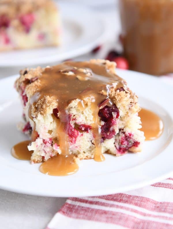piece of cranberry coffee cake with warm vanilla sauce on white plate