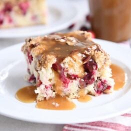 piece of cranberry coffee cake with warm vanilla sauce on white plate