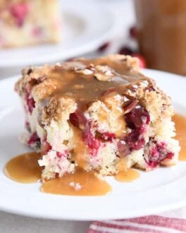 piece of cranberry coffee cake with warm vanilla sauce on white plate
