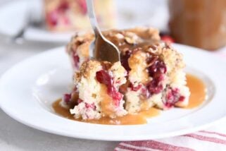 fork taking bite of cranberry coffee cake and warm vanilla sauce