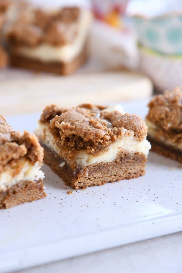 Gingerbread cookie cheesecake bar on white speckled tray.