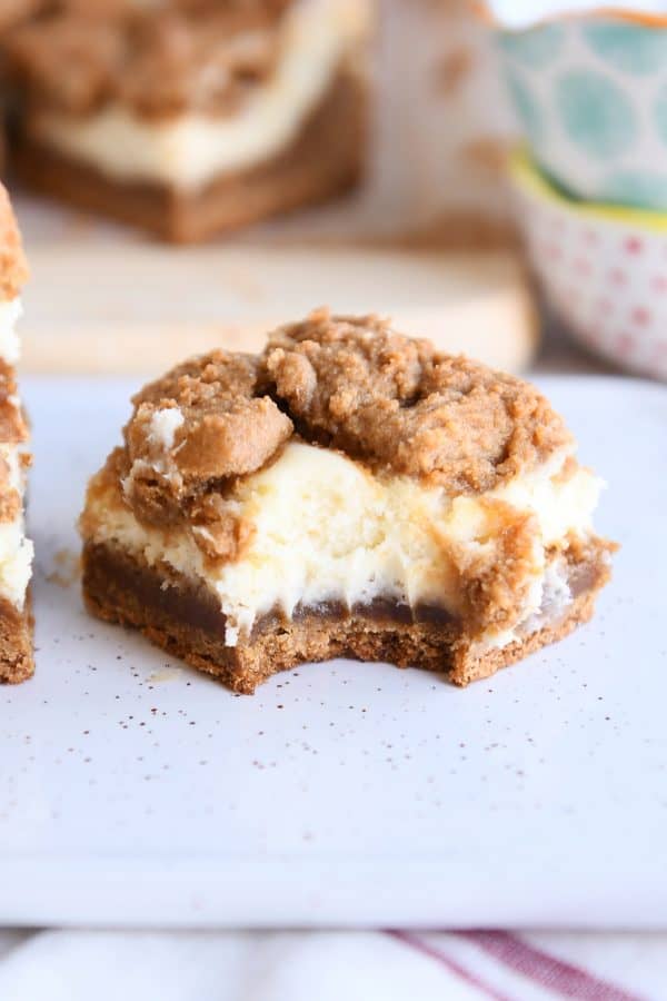 gingerbread cookie cheesecake bar with bite taken out on white speckled tray