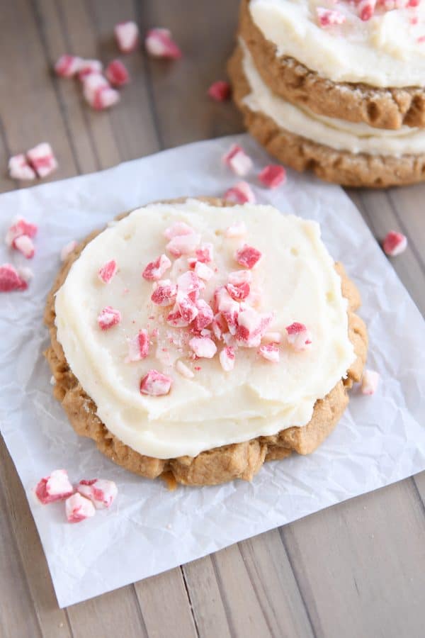 Frosted gingerbread sugar cookie on white parchment paper with peppermint crunch candies.