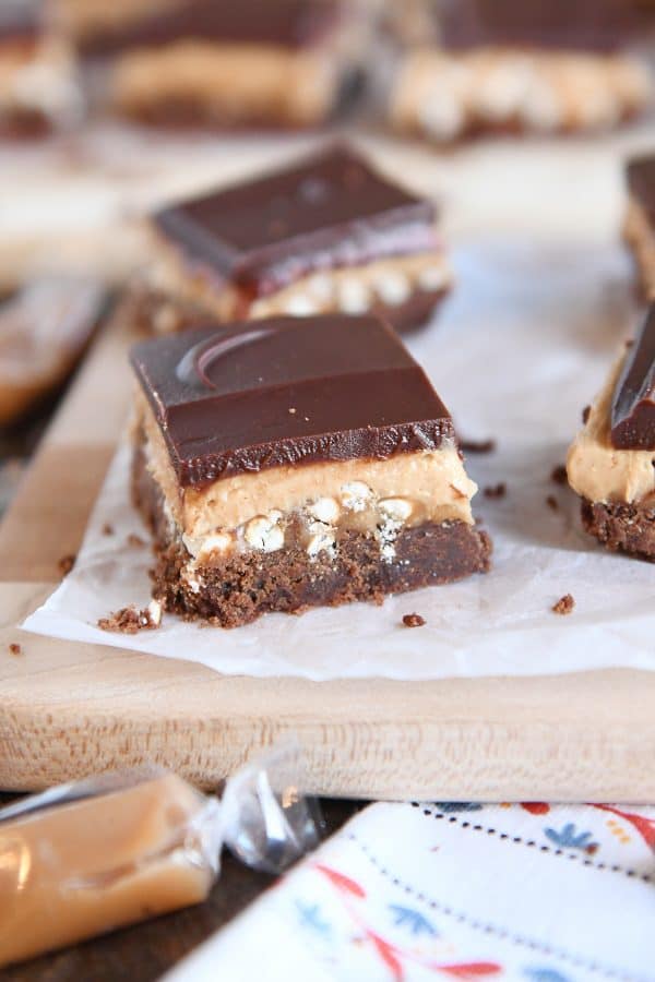 Peanut butter pretzel caramel chocolate bar square on piece of white parchment paper.