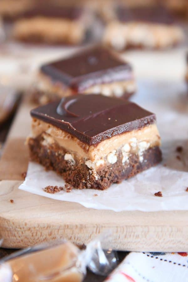 Peanut butter pretzel caramel chocolate bar square on piece of white parchment paper.