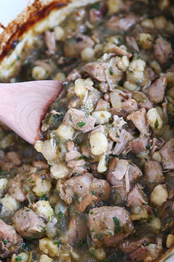 Scooping slow cooker posole with wooden spoon.