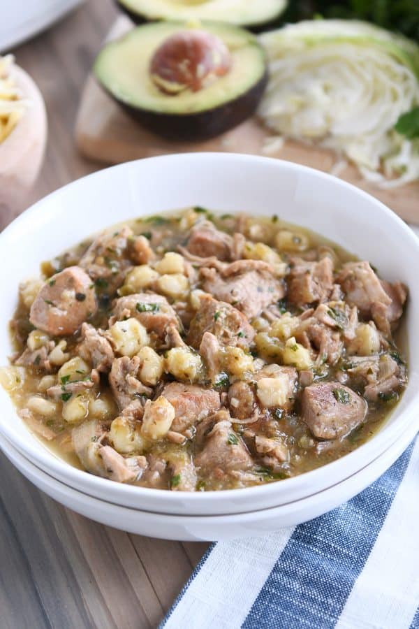 white bowl with slow cooker posole on wood board