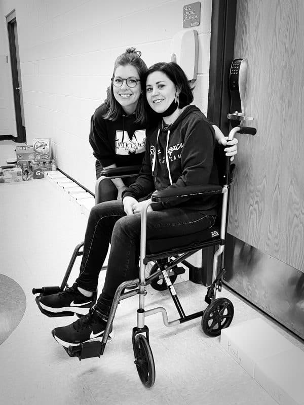 woman in wheelchair with friend standing by her side