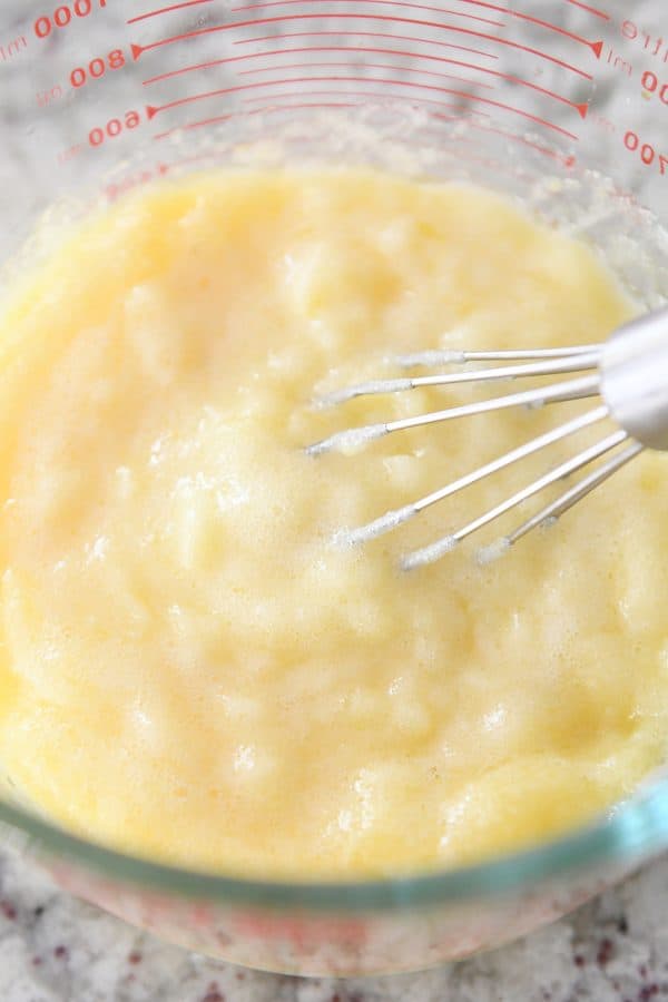 Whisking lumpy instant pot lemon curd in glass bowl.