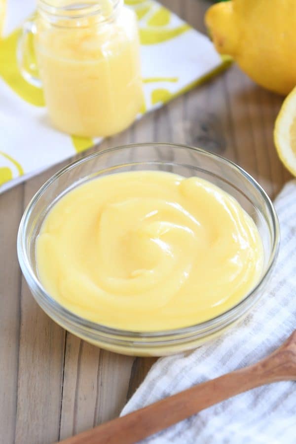 Glass bowl with lemon curd on striped napkin.