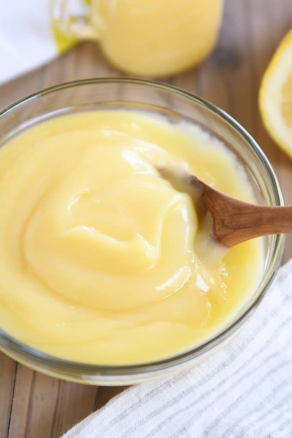 Glass bowl with instant pot lemon curd and wooden spoon.