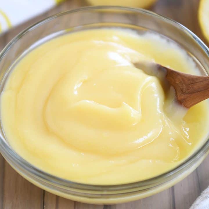 Glass bowl with easy-to-prepare lemon curd and wooden spoon