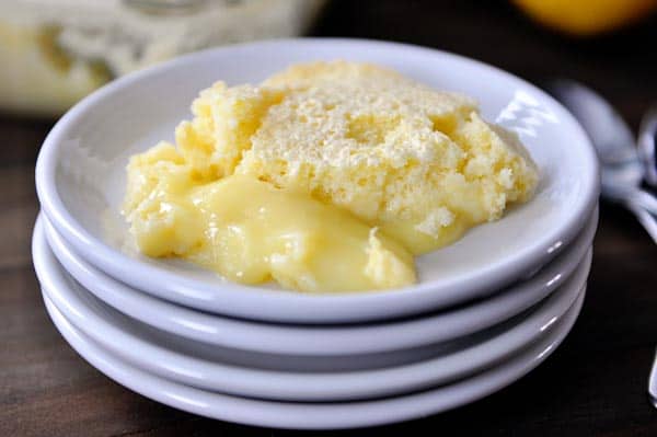 A stack of white plates with a serving of lemon pudding cake.