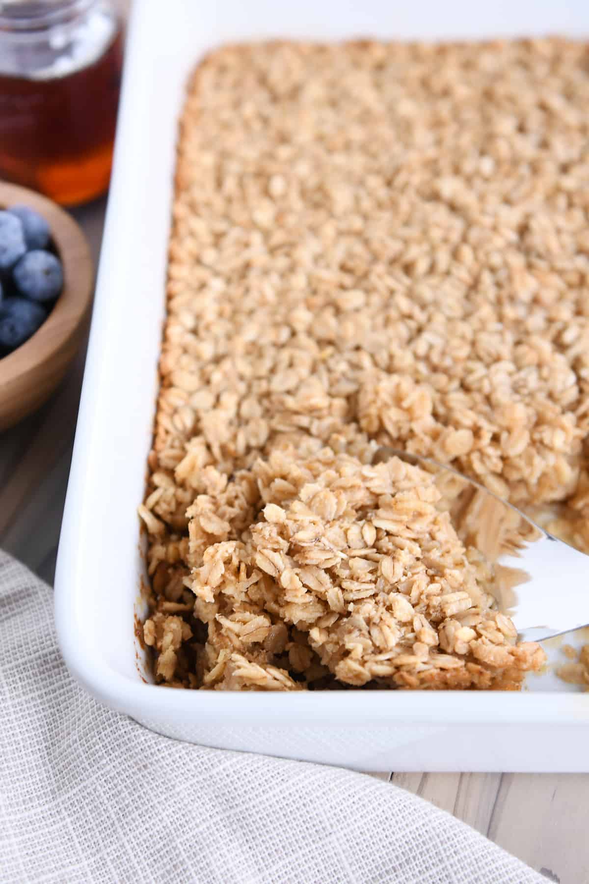 Baked oatmeal in white dish with spoon scooping out a portion.