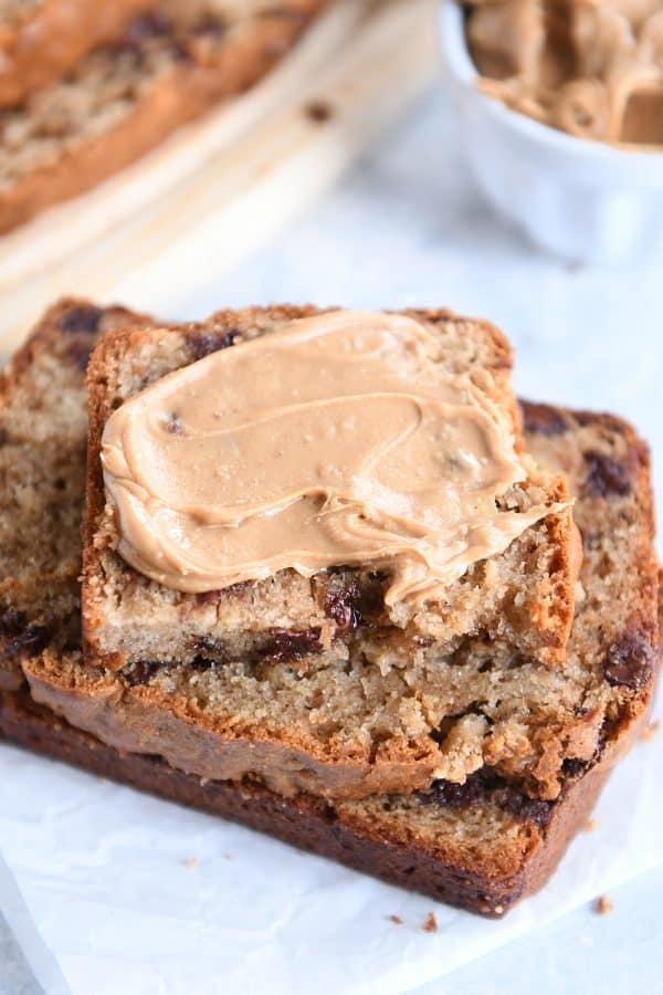 Stack of peanut butter banana bread slices with peanut butter spread on top.