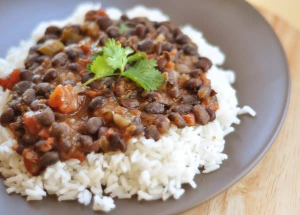White rice topped with tomato and black bean mixture on a gray plate.