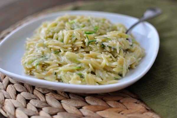 White plate with creamy cooked orzo and herbs.