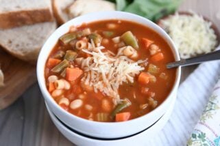 minestrone soup in two stacked white bowls with parmesan cheese