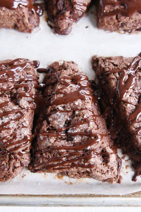 Three triple chocolate scones with chocolate glaze drizzled on top.