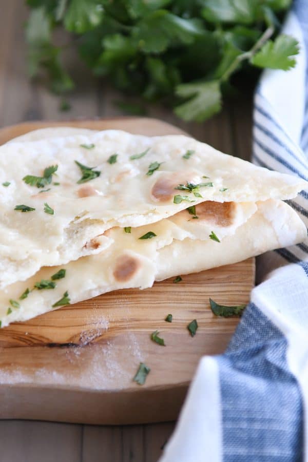 Yogurt flatbread torn in half on wood cutting board.