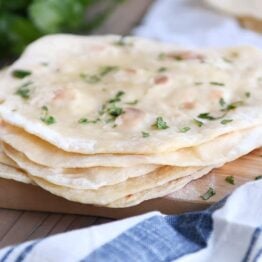 stack of easy yogurt flatbread on wood cutting board sprinkled with parsley