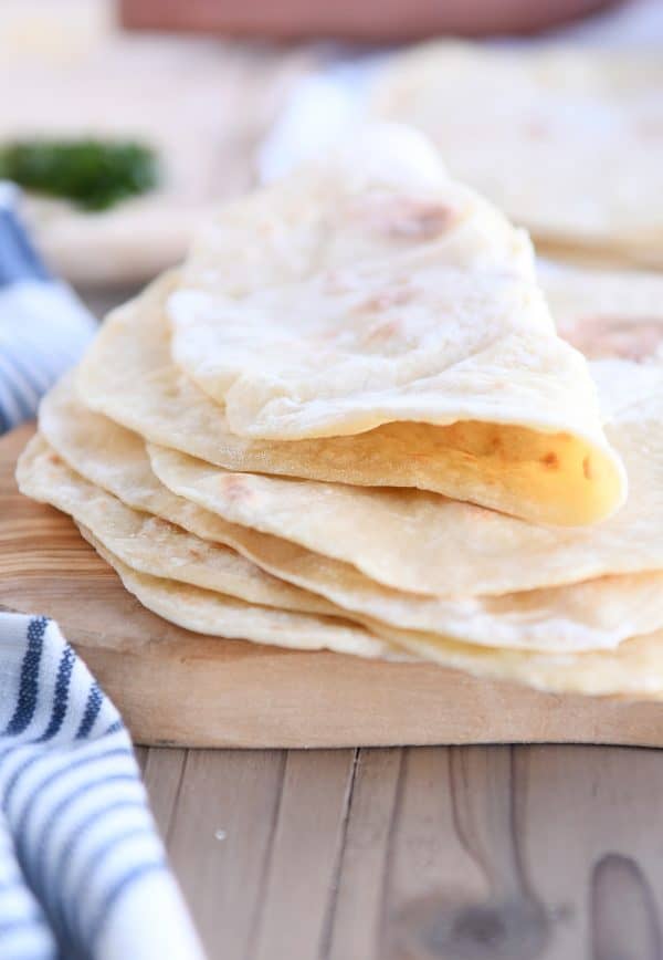 Folded piece of yogurt flatbread on stack of four flatbreads.