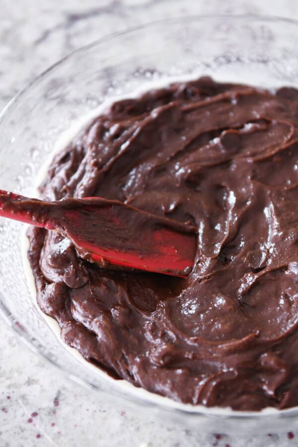 Spreading brownie batter in pie plate with red spatula.