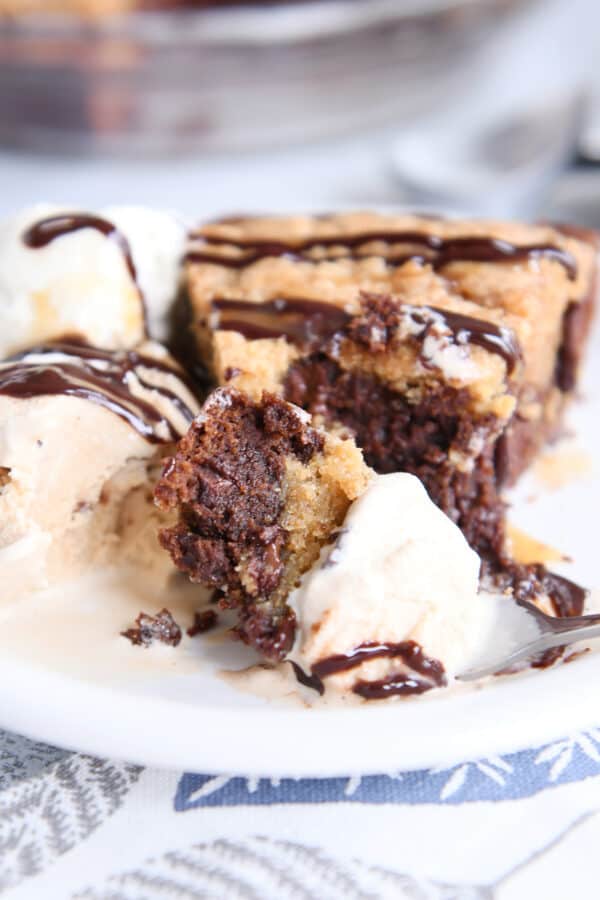 Ice cream, brookie pie, and chocolate drizzle on white plate.