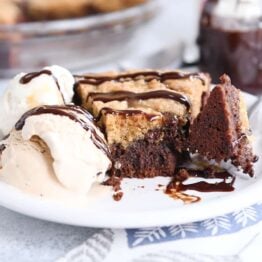 bite of brookie pie cut out with fork on white plate with ice cream and chocolate drizzle