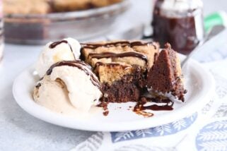 bite of brookie pie cut out with fork on white plate with ice cream and chocolate drizzle