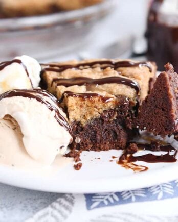 bite of brookie pie cut out with fork on white plate with ice cream and chocolate drizzle