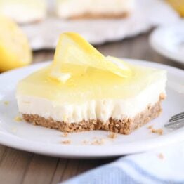 square of lemon white chocolate cream bar on white plate with bite taken out