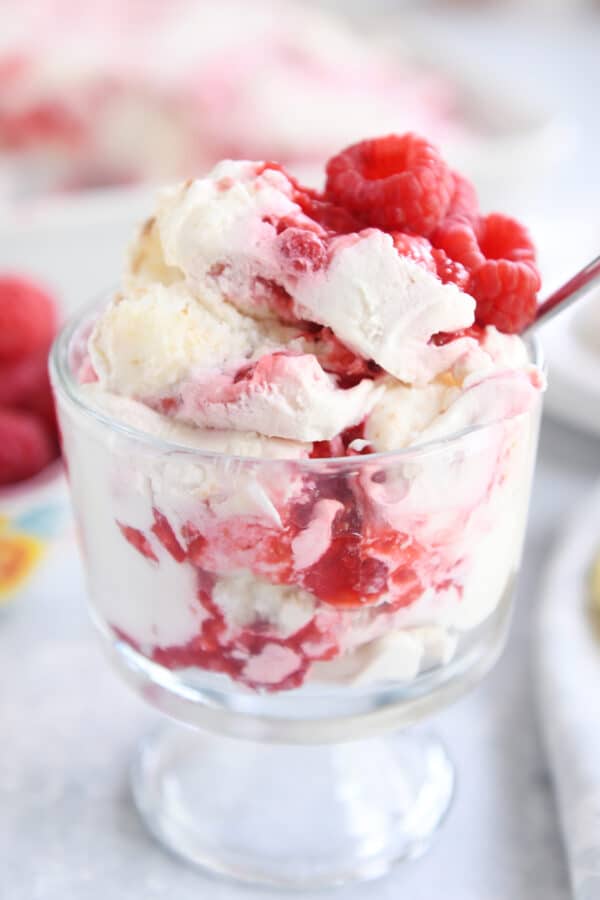 Raspberry cream angel food cake dessert piled in small glass trifle dessert dish.