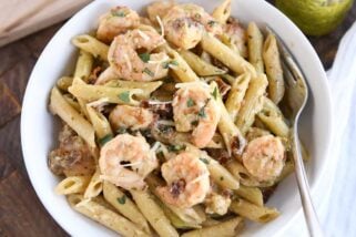 pasta with shrimp, parmesan and sun-dried tomatoes in white bowl with fork