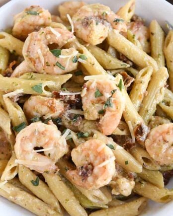 pasta with shrimp, parmesan and sun-dried tomatoes in white bowl with fork