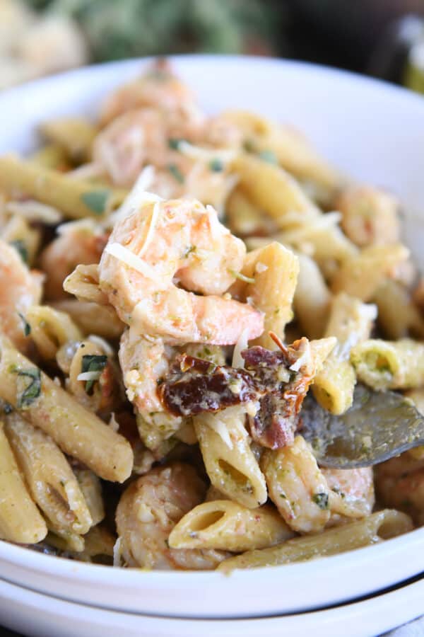 Shrimp, pasta, sun-dried tomatoes in white bowl with fork.