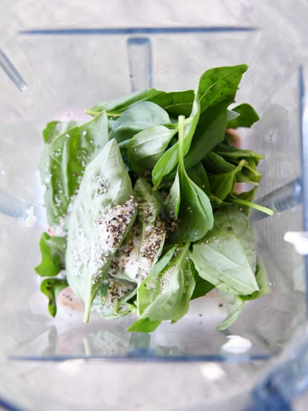 Blender with fresh basil leaves, salt and pepper.